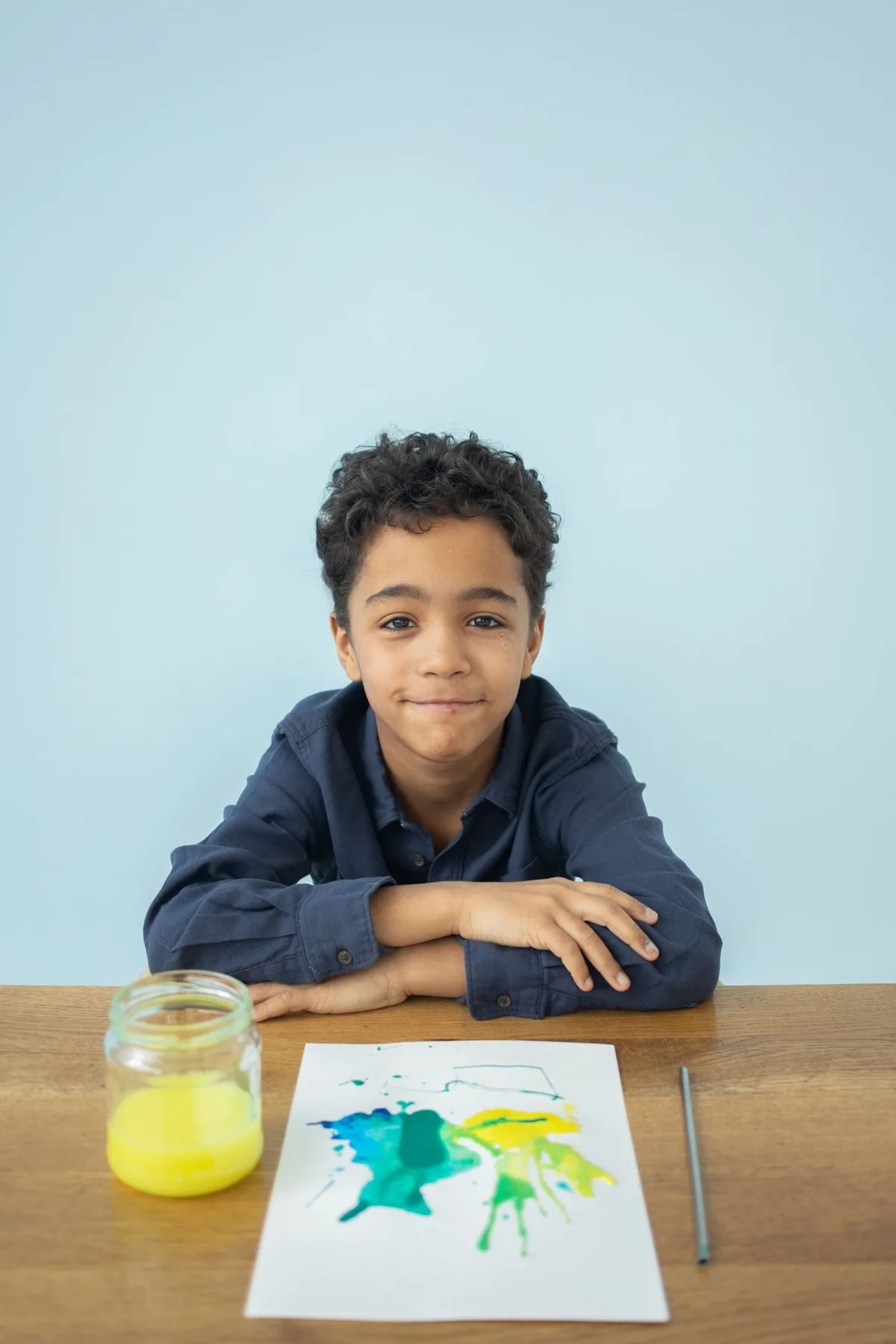 A child sitting at a wooden table with a watercolor painting