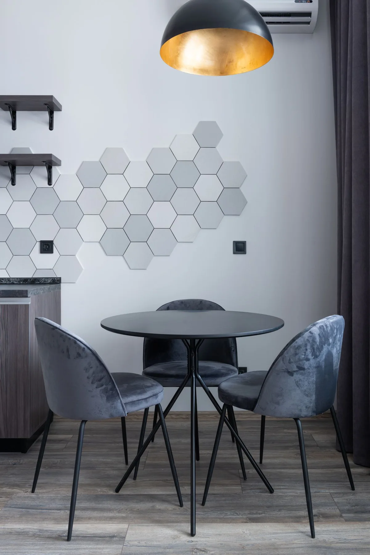 A round dining table with upholstered chairs beneath a pendant lamp